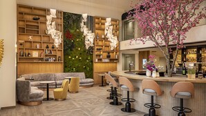 A modern bar area with a curved counter, bar stools, and a seating area with a sofa and round tables. - Best Western Plus Hotel Saint-Roch Orleans (Orleans)