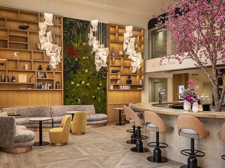 Eine moderne Bar mit einer gebogenen Theke, Barhocker und einer Sitzecke mit einer Couch und runden Tischen.