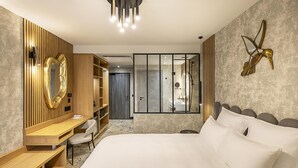 A modern hotel room with a large bed, a desk, a wardrobe, and a bathroom visible through a glass door. - Best Western Plus Hotel Saint-Roch Orleans (Orleans)
