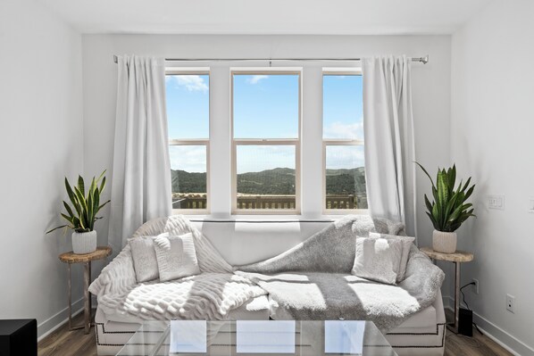 Relax in a serene mountain view room with a comfortable sofa, potted plants, and a minimalist design.