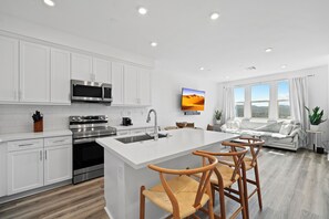 Enjoy cooking in the kitchen with a central island, bar stools, stainless steel appliances, and ample counter space.