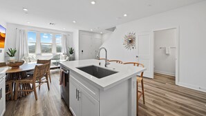 Una cocina moderna con una isla central, armarios blancos y un amplio ventanal con vistas al exterior.