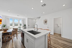 Enjoy meals in the well-lit kitchen with a central island, sink, and dining table.