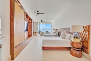 A modern hotel room with a large bed, a wooden headboard, a ceiling fan, and a view of the mountains through the window. - Casa Dinamita, a Luxurious Ocean Front Villa with Private Bowling Alley! (Punta Mita)