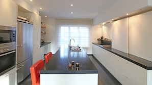Una cocina moderna con una isla central, electrodomésticos de acero inoxidable y un ventanal luminoso.