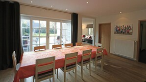Un comedor con una mesa larga, sillas y vistas al exterior a través de amplios ventanales.