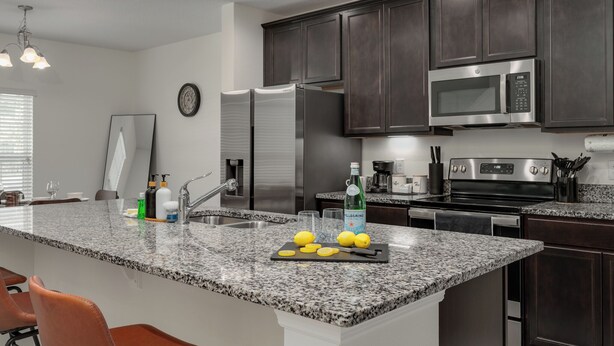 Una cocina moderna con gabinetes de madera oscura, electrodomésticos de acero inoxidable y encimera de granito.