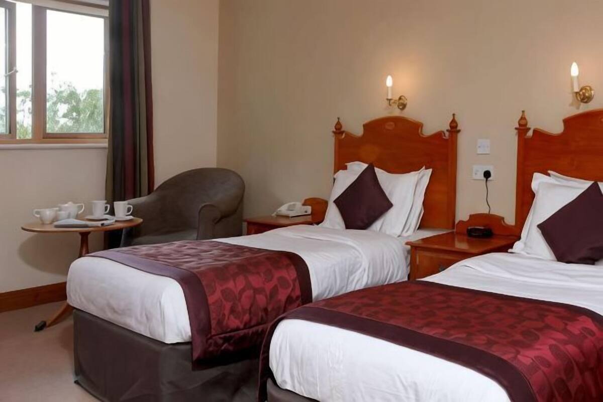 Een hotelkamer met twee bedden, een bureau, een stoel en een raam.