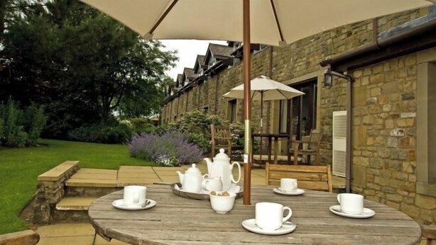 A round wooden table with white teapots, cups, and saucers, set outdoors under a large umbrella. - Best Western Preston Garstang Country Hotel and Golf Club (Barnacre-with-Bonds)