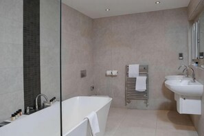Une salle de bain moderne avec une baignoire, deux lavabos, un porte-serviettes et un miroir.