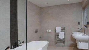 A modern bathroom with a bathtub, two sinks, and a towel rack.