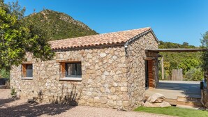 Ein Haus aus Stein mit Ziegeldach, einem kleinen Fenster und einer Holztür.