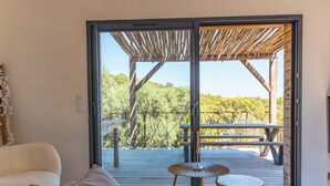 Ein Zimmer mit einer Schiebetür zu einem Außenbereich mit Holzzugang, einer hölzernen Pergola und einem Picknicktisch.