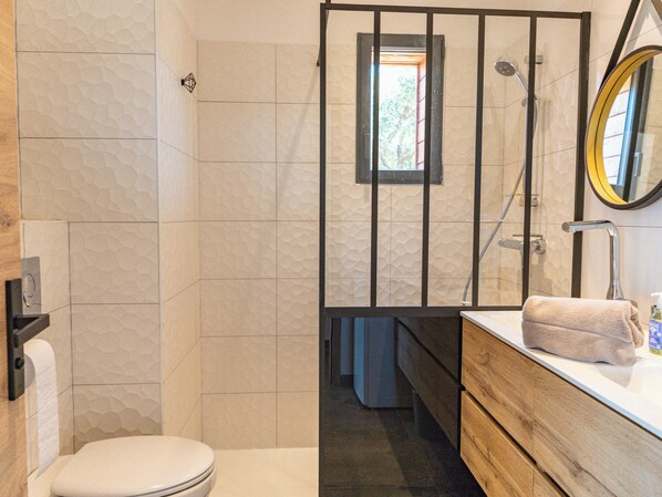 A bathroom with a toilet, a shower area, and a sink with a towel.