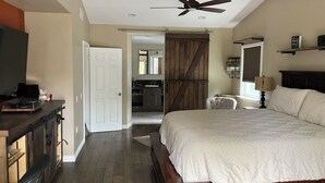 A bedroom with a large bed, a desk with a computer, a chair, and a ceiling fan. - Oceanside tranquility (Oceanside)