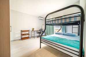 A bunk bed with a desk and chair, a wooden bench, and a window with curtains.