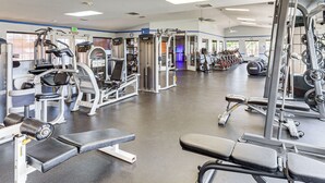 Ein Fitnessstudio mit verschiedenen Trainingsgeräten, Bänken und Gewichten.
