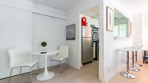 Eine moderne Küche mit Edelstahlgeräten, ein weißer Essbereich mit rundem Tisch und Stühlen, und eine kleine Pflanze auf dem Tisch.