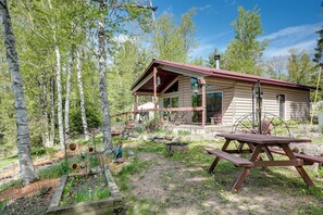 Un chalet rustique doté d’une véranda, entouré d’un jardin et d’arbres.