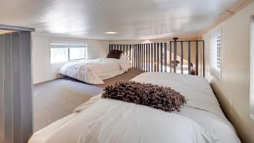 A bedroom with two beds, a window, and a door.