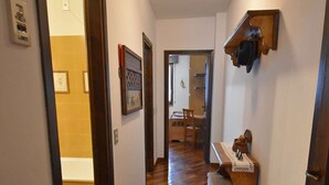 A hallway with wooden flooring, a wooden bench, and a wall-mounted coat rack. - Presanella Alpine Apartment Mhd (Madonna di Campiglio)