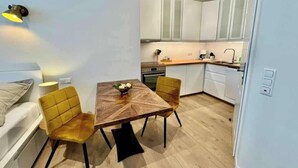 Un espacio habitable compacto con comedor, kitchenette y una pequeña zona de estar.