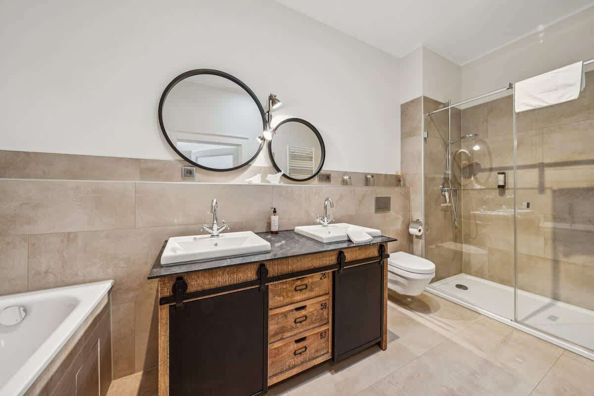 Ein modernes Badezimmer mit einem Doppelwaschtisch, einer Toilette, einer Duschkabine und einer Badewanne.