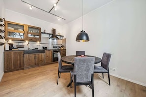 Una cocina moderna con armarios de madera, una mesa de comedor redonda y una lámpara colgante.