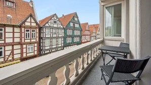 Ein Balkon mit Blick auf traditionelle Fachwerkhäuser, einem Tisch und zwei Stühlen.