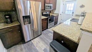 Una cocina con electrodomésticos de acero inoxidable, gabinetes de madera y encimeras de granito, además de un lavavajillas.