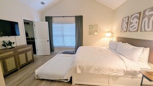 Un dormitorio con cama, televisión, escritorio y ventilador de techo.