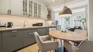 Una cocina moderna con armarios grises, una mesa redonda de madera y una lámpara colgante.