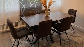 Een moderne eetruimte met een rechthoekige tafel, zes stoelen en drie hanglampen.