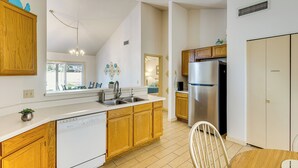 A modern kitchen with wooden cabinets, a stainless steel refrigerator, and a dishwasher.