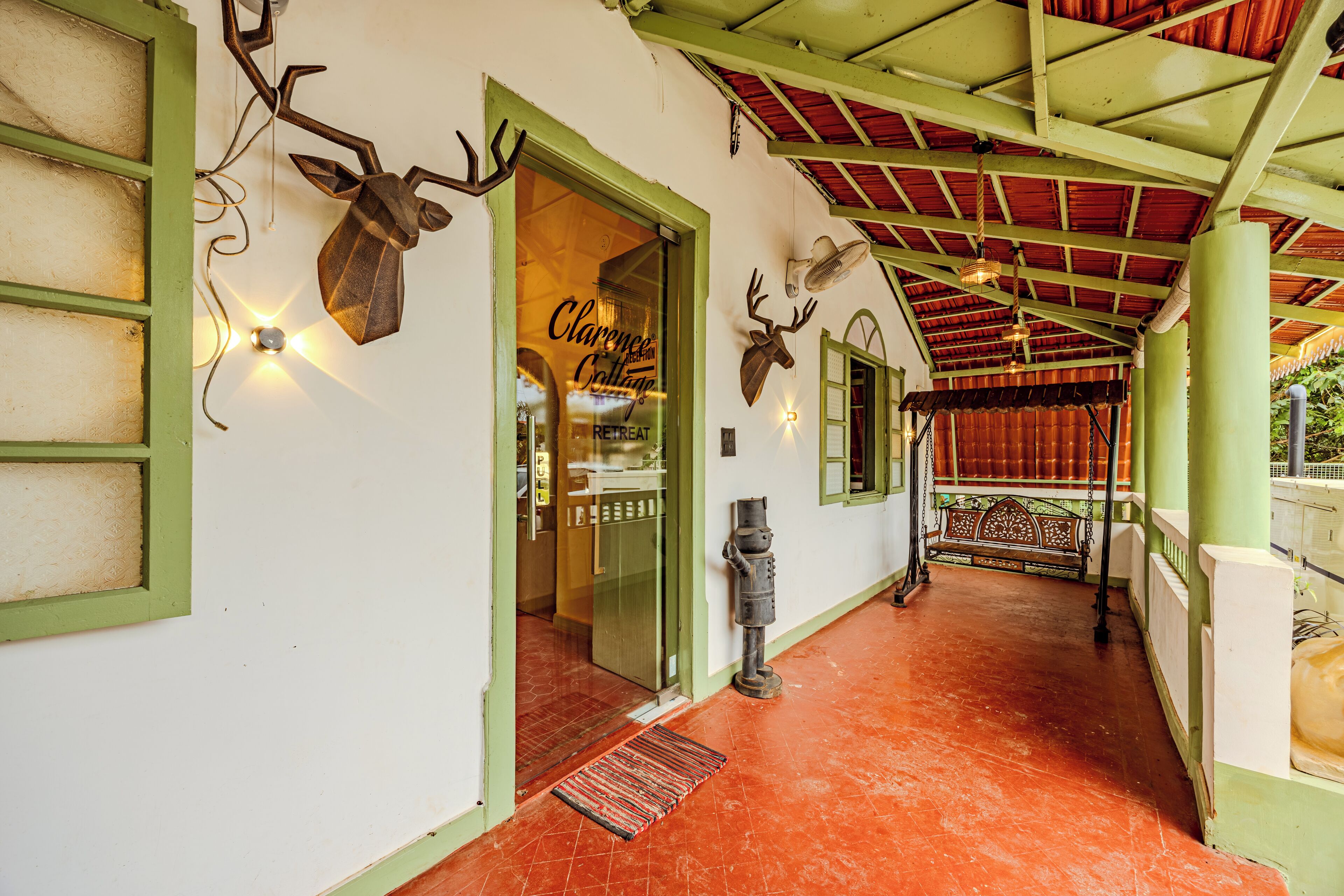 Ein Korridor mit roten Fliesen, grünen Wänden und einer Holztür mit der Aufschrift 'Clarence Lodge Retreat'.