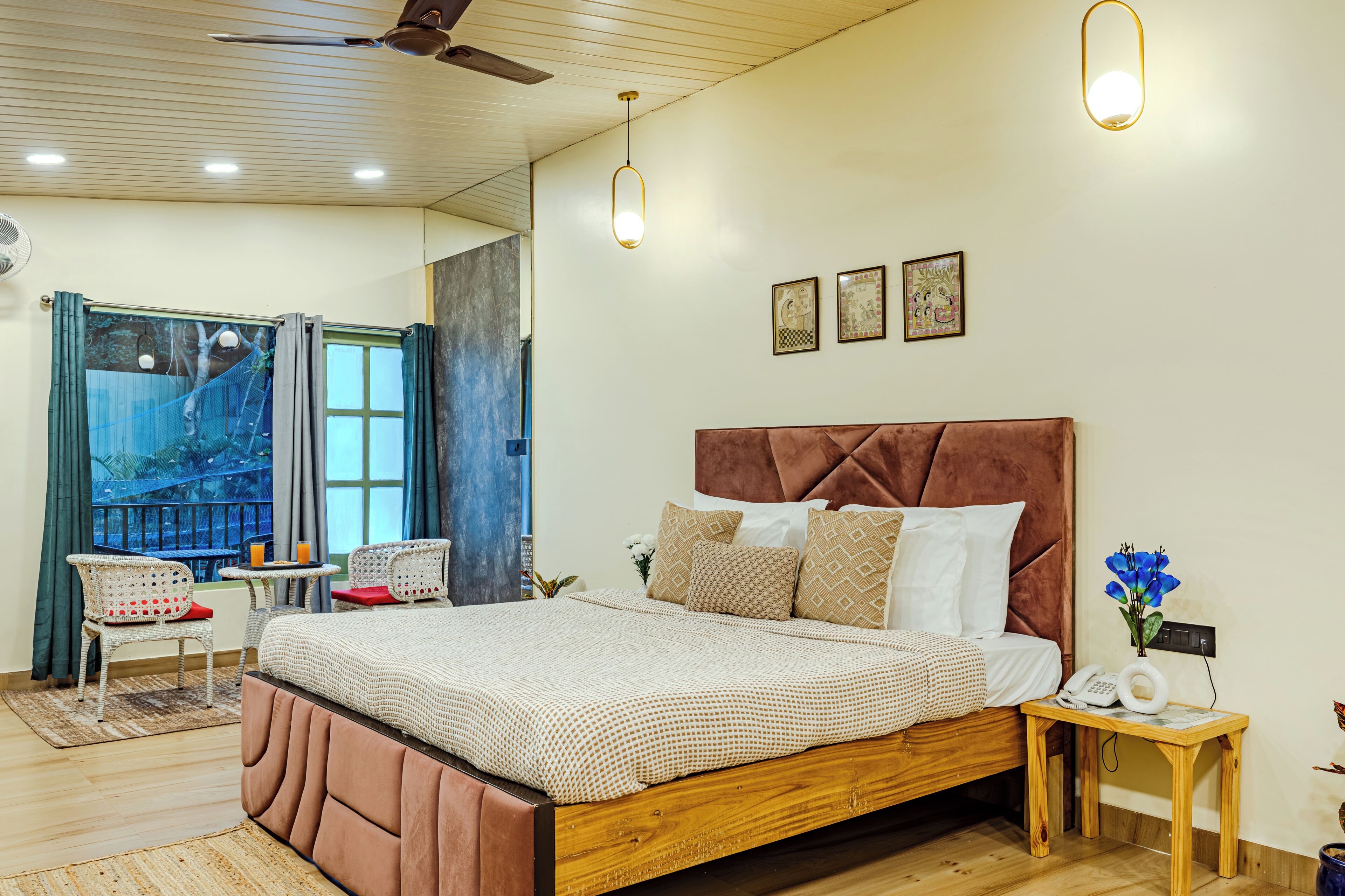 A bedroom with a large bed, a wooden nightstand, a ceiling fan, and a window with curtains.