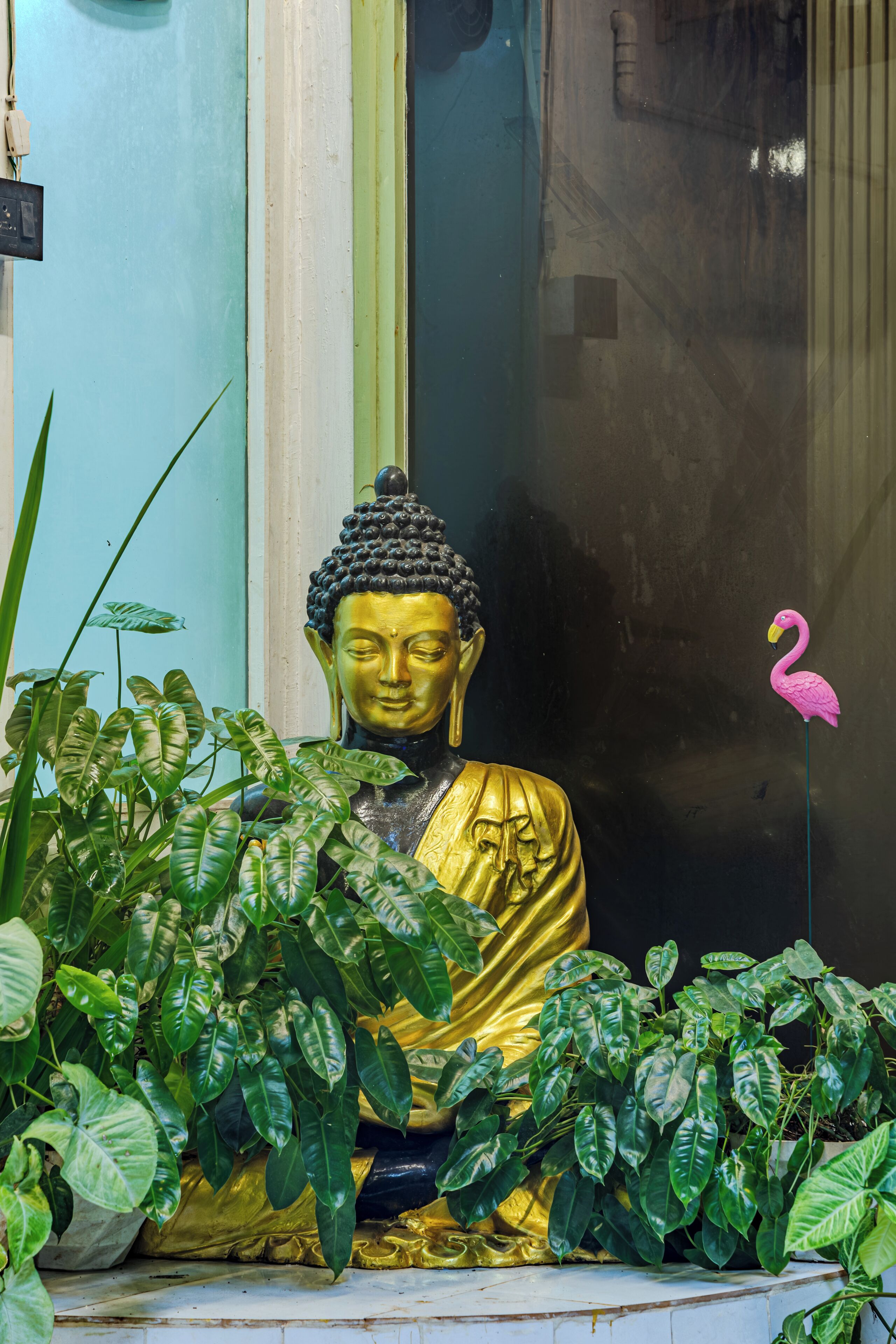 A golden Buddha statue surrounded by lush green plants.