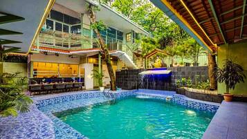 Una piscina al aire libre, sombrillas, sillones reclinables de piscina