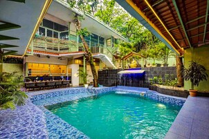 Una piscina al aire libre, sombrillas, sillones reclinables de piscina