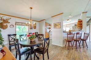 A dining area with a round table, wooden chairs, and a chandelier. - Lakefront Home w/ Beach Access, Deck & Dock (Fountain)
