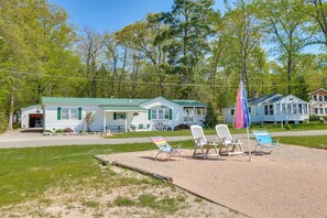 A house with a green roof, a porch with outdoor seating, and a flagpole. - Lakefront Home w/ Beach Access, Deck & Dock (Fountain)