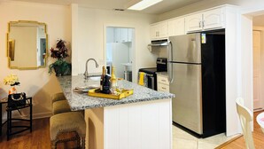 Una cocina moderna con armarios blancos, un refrigerador de acero inoxidable y una encimera de granito.