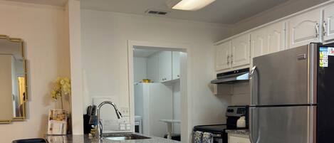 A modern kitchen with a granite countertop, stainless steel appliances, and white cabinetry.