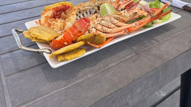 A seafood platter on a table with a view of the ocean and hills. - Hotel Cocotal (Isla Grande)
