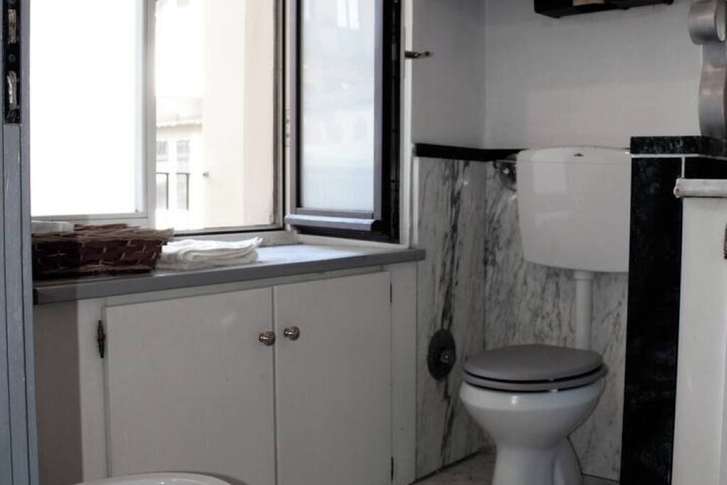 A bathroom with a toilet, a window, and cabinets.