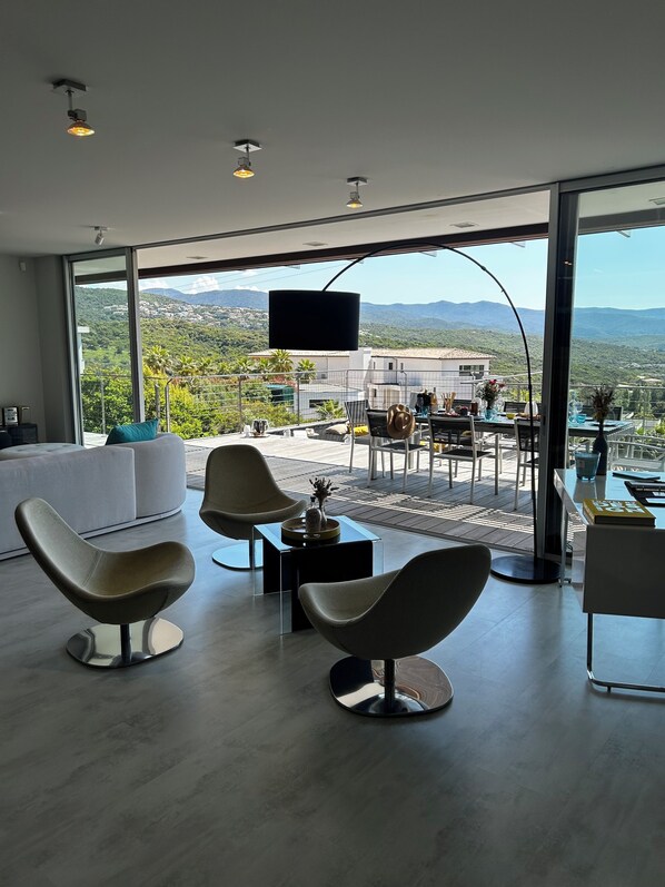 Una sala de estar moderna con un amplio ventanal que da a una terraza exterior.