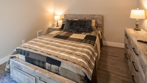 Une chambre à coucher avec un lit en bois, une table de chevet avec une lampe et une commode également dotée d’une lampe.