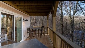 Une terrasse en bois avec une table et des chaises, donnant sur une zone boisée.