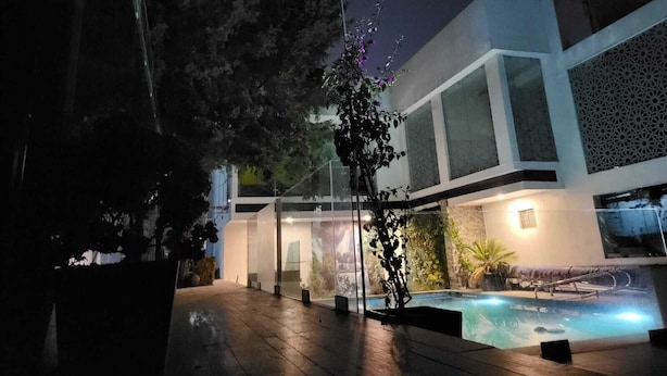 Un bâtiment moderne doté d’une façade en verre, d’un espace piscine et d’un éclairage extérieur.
