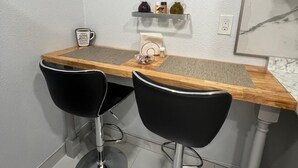 A kitchen with a wooden countertop, two black bar stools, and a framed rule for the kitchen on the wall. - Charming guesthouse B 1-bedroom in North Lakeland with full kitchen, WiFi, AC (Lakeland)